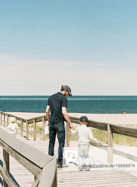 Ein Vater  der seinen Sohn an der Hand hält  am Strand