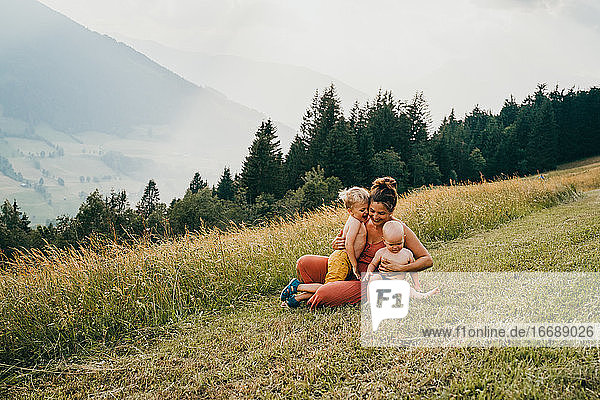 Mom and kids hugging in the mountains sitting on ground