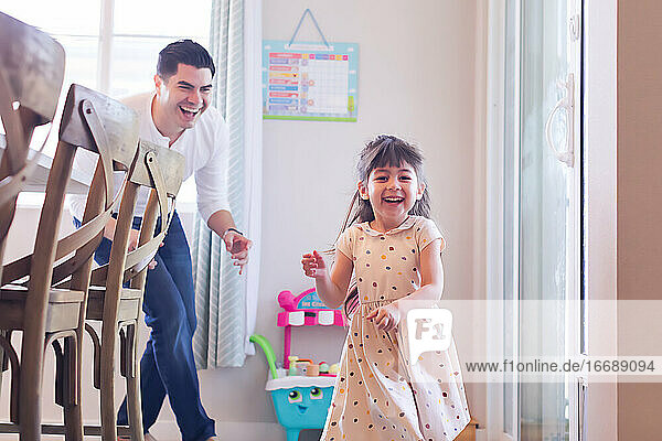 Dad running after his daughter in the kitchen.