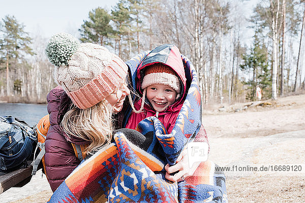Mutter und Tochter lachen und umarmen sich bei einem Picknick