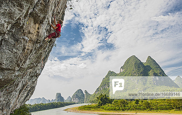 junger Mann beim Klettern an einer steilen Felswand in Yangshuo / China
