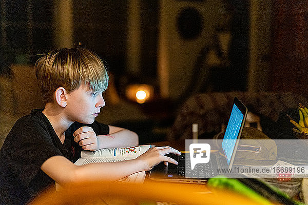 Junge Person arbeitet beim abendlichen Fernunterricht am Laptop
