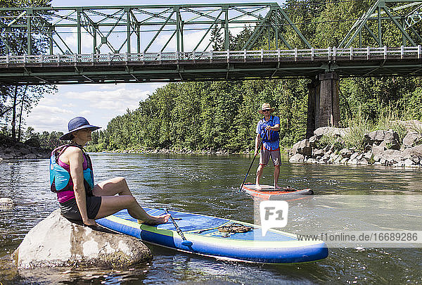 A young couple enjoy the river on their SUPs in Oregon.