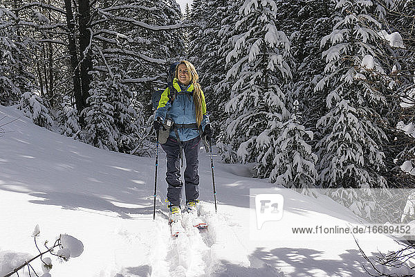 Lächelnde junge Wanderin beim Splitboarden auf einem schneebedeckten Berg