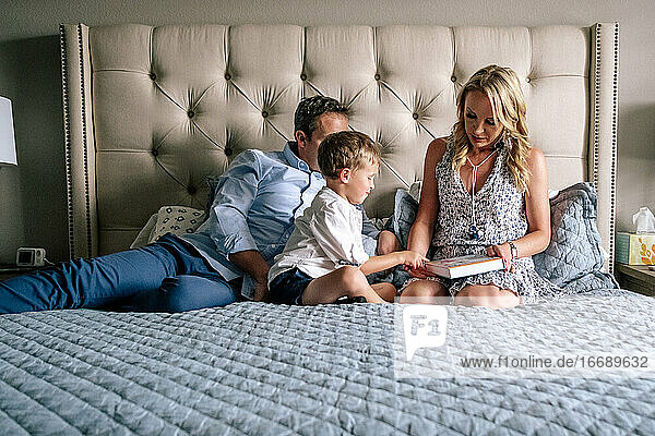 Horizontal portrait of a family sitting on a bed reading a book