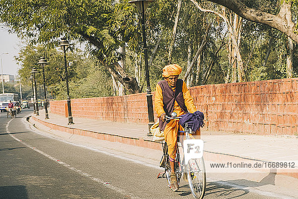 Ein alter Mann fährt mit dem Fahrrad durch die Straßen von Agra  vorbei am Agra Fort.