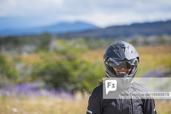 Frau in Motorradkleidung und Helm lacht in die Kamera  Puerto Natal