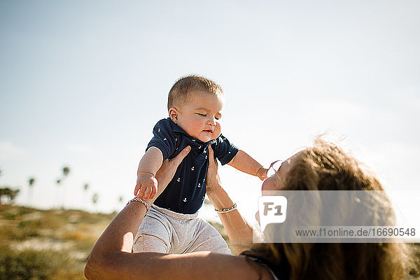 Grandmother Holding Grandson High While Standing on Beach