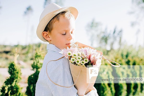 Hübscher Junge hält einen schönen Blumenstrauß im Sommer