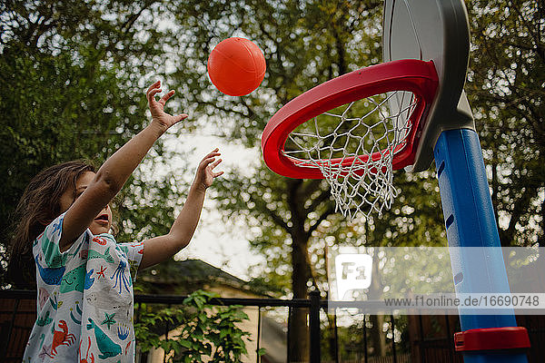 kleines Mädchen spielt draußen Basketball