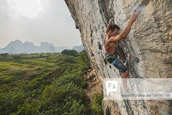 Mann klettert an einer Felswand in Yangshuo / China