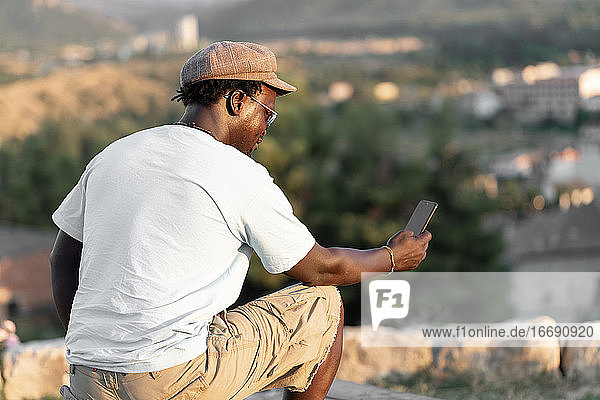 afroamerikanischer schwarzhäutiger Mann mit Mobiltelefon und lockigem Haar