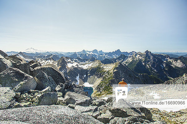 Mann steht auf einem Felsbrocken mit Blick auf die Berge  Mount Baker.