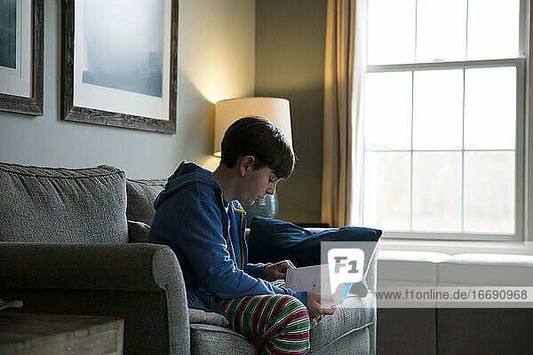 Close Up Seitenansicht von Teen Boy sitzt auf Couch Lesen Geburtstagskarte