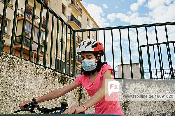 Mädchen  das auf einer leeren Straße in seinem Viertel Fahrrad fährt  trägt Fa