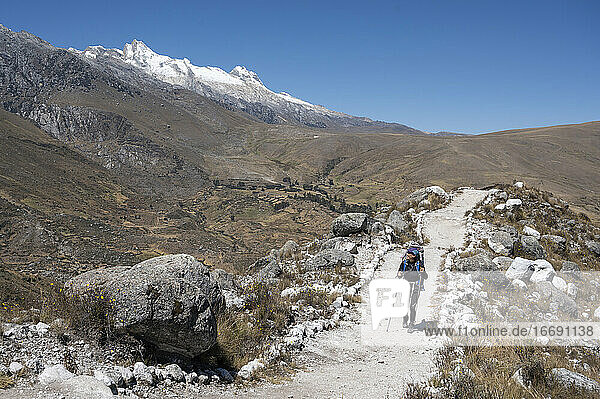 Eine Frau mit Rucksack und Stöcken beim Wandern in der Cordillera Blanca