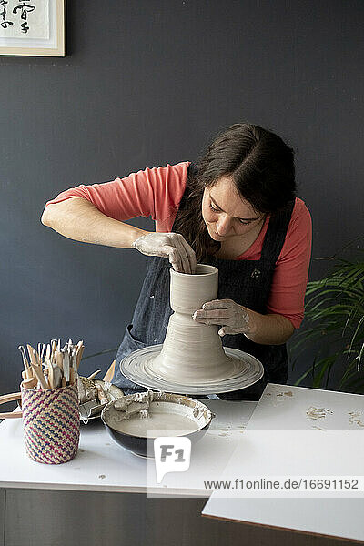 Junge Frau bearbeitet Ton in einem Keramikstudio