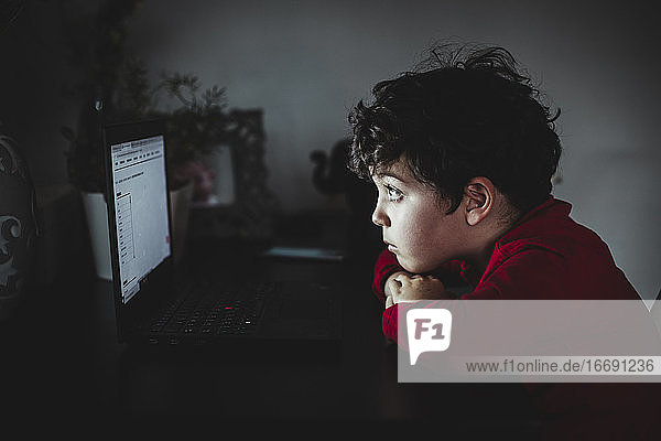 Ein Kind schaut auf seinen Computer  während es wegen Covid-19 eingesperrt ist.