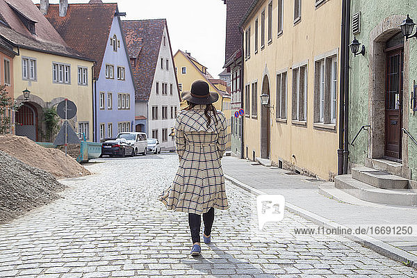 Eine Frau in einem langen Mantel  die durch die Straßen von Deutschland läuft