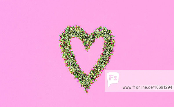 Herz mit Marihuana auf rosa Hintergrund gemacht. Weed und Liebe Konzept.