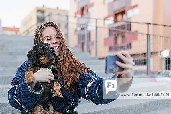 Alternative junge erwachsene Frau macht ein Selfie-Foto mit ihrem Hund