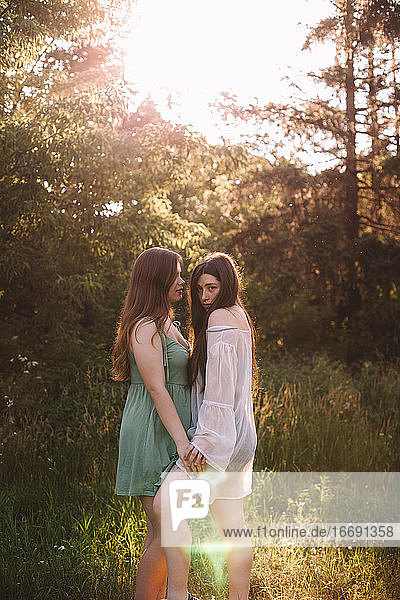 Porträt eines lesbischen Paares  das im Sommer im Wald steht