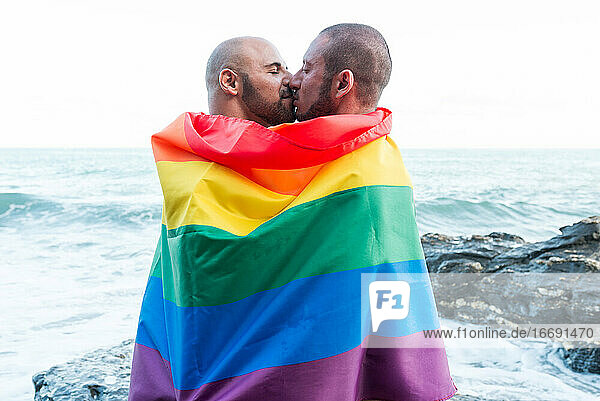 Lgbt Stolz Konzept. Homosexuelles Paar  das sich liebevoll umarmt  eingewickelt in die Regenbogenflagge.