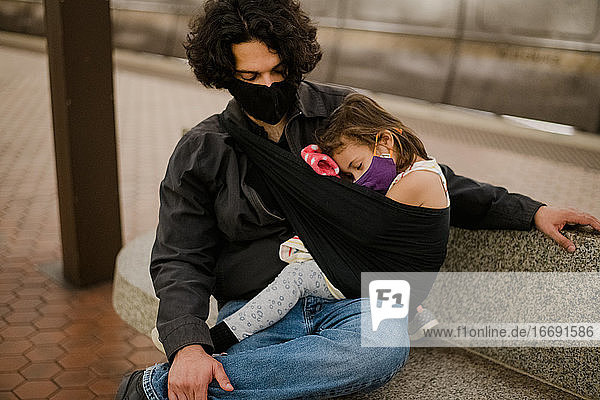 daughter sleeping in sling on dad wearing face masks