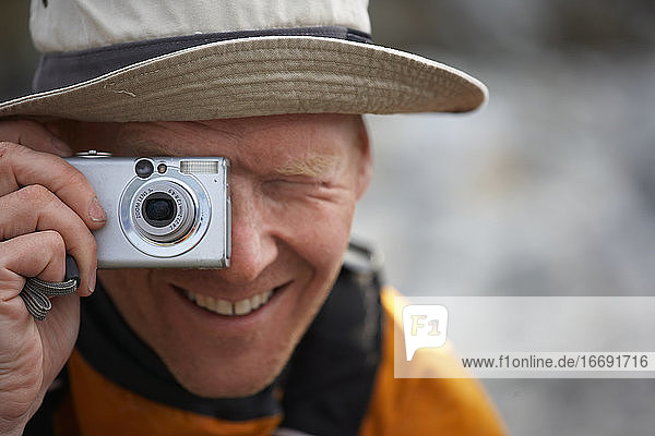Mann  der in Grönland ein Foto mit einer digitalen Point-and-Shoot-Kamera macht