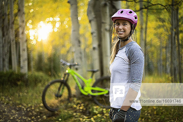 Porträt einer lächelnden Mountainbikerin im Wald