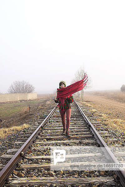 Vorderansicht einer Frau mit Kopftuch  die auf einer Eisenbahnstrecke geht