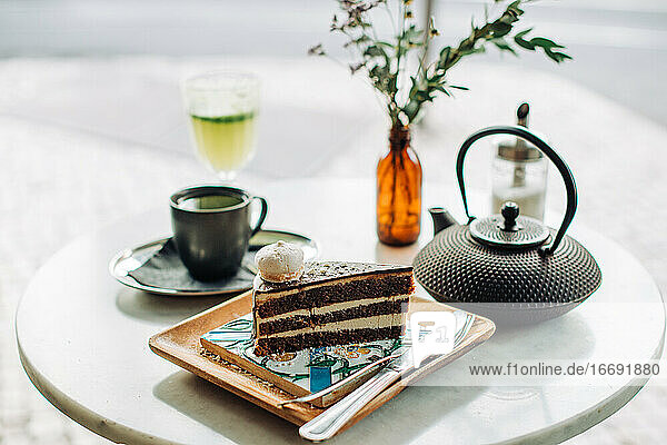 Stück Schokoladenkuchen  Teekanne  Tasse Tee auf dem Tisch in einem Café im Freien