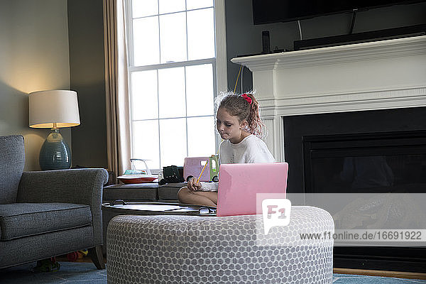 Junges Mädchen arbeitet an einem Laptop-Computer auf einem Wohnzimmersofa sitzend