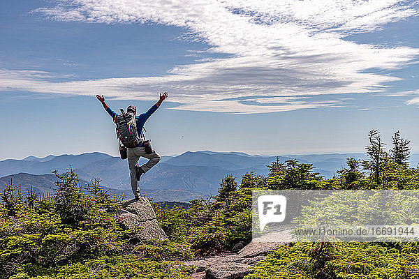Mann übt Yoga-Balance-Pose auf dem Gipfel eines Berges.