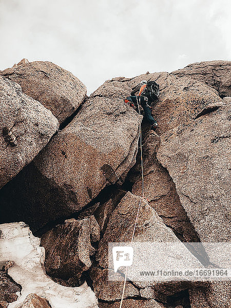 Bergsteiger beim Aufstieg durch eine steile Felswand mit Steigeisen  die durch ein Seil gesichert sind