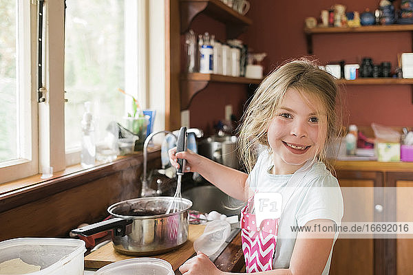 Junges Mädchen lächelnd und Schneebesen heißen Backmischung in chaotisch Küche
