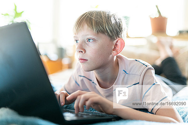 Close up Porträt von Teenager arbeiten am Laptop im Inneren auf hellen sonnigen Tag