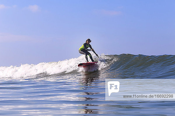 SUP-Surferin auf einer Welle