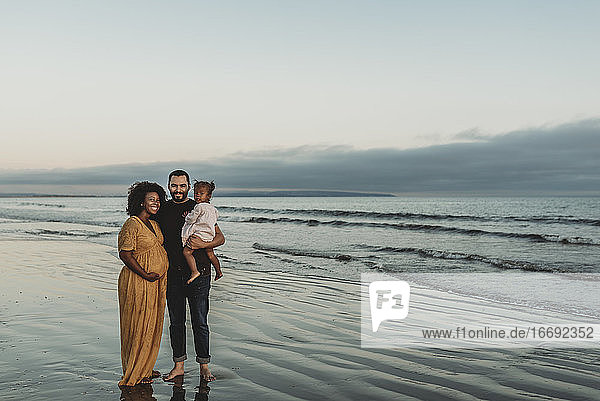 Portrait of family of three smiling at the beach