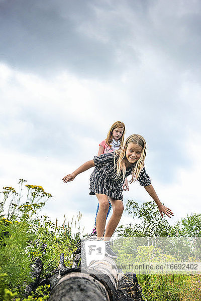 Two Young Girls Walking on Log