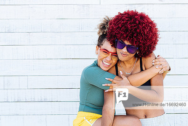 Zwei attraktive Latino-Mädchen mit Afro-Haar  die sich freundschaftlich umarmen.