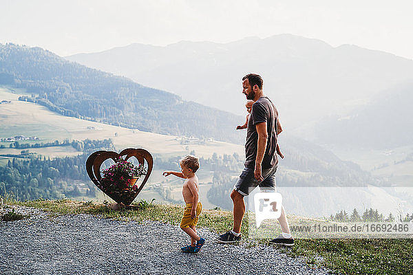 Father and sons walking by the mountains in the summer