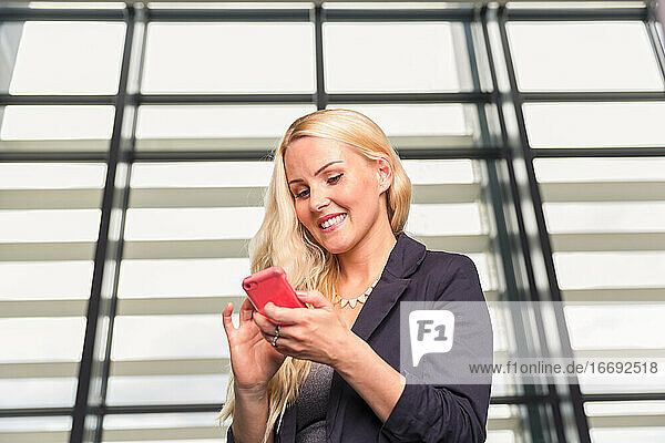 Glückliche Frau mit Smartphone in der Nähe der Wand
