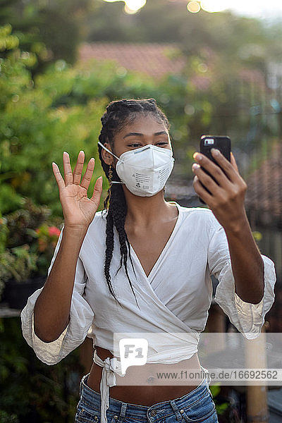 Junge schwarze Frau mit Gesichtsmaske bei einem Videogespräch