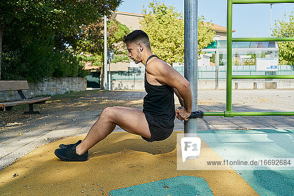 Seitenansicht eines Mannes  der an einem sonnigen Tag in einem Park Gymnastik macht