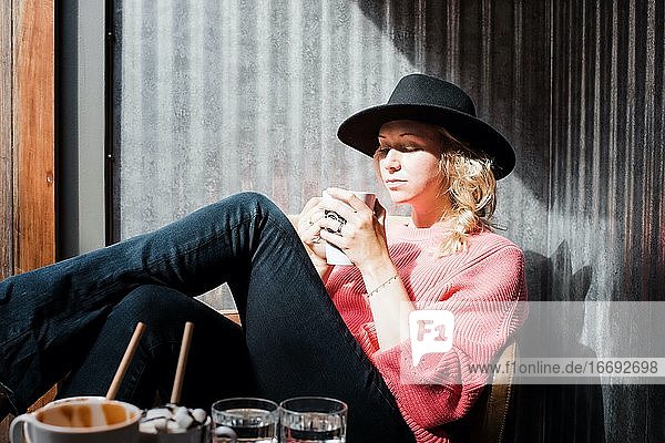 Frau sitzt in einem Café und schaut auf ihren Kaffee