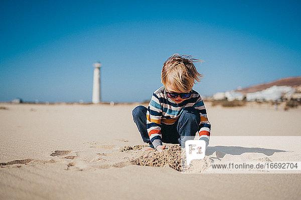Junge Kind Kind spielt am Strand an einem kalten und windigen Tag