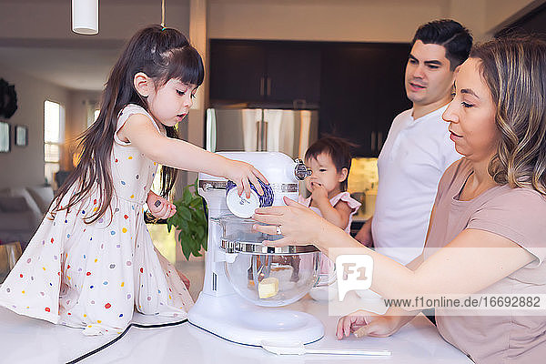 4-köpfige Familie in der Küche  die Mutter hilft der älteren Tochter beim Plätzchenbacken.