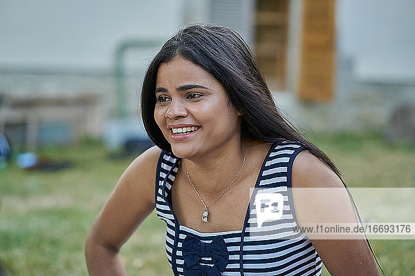 Young straight hair woman smiling in a park wearing a striped blouse