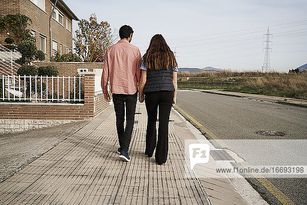 Junges Paar geht zusammen und hält sich an den Händen auf der Straße. Romantisches Konzept